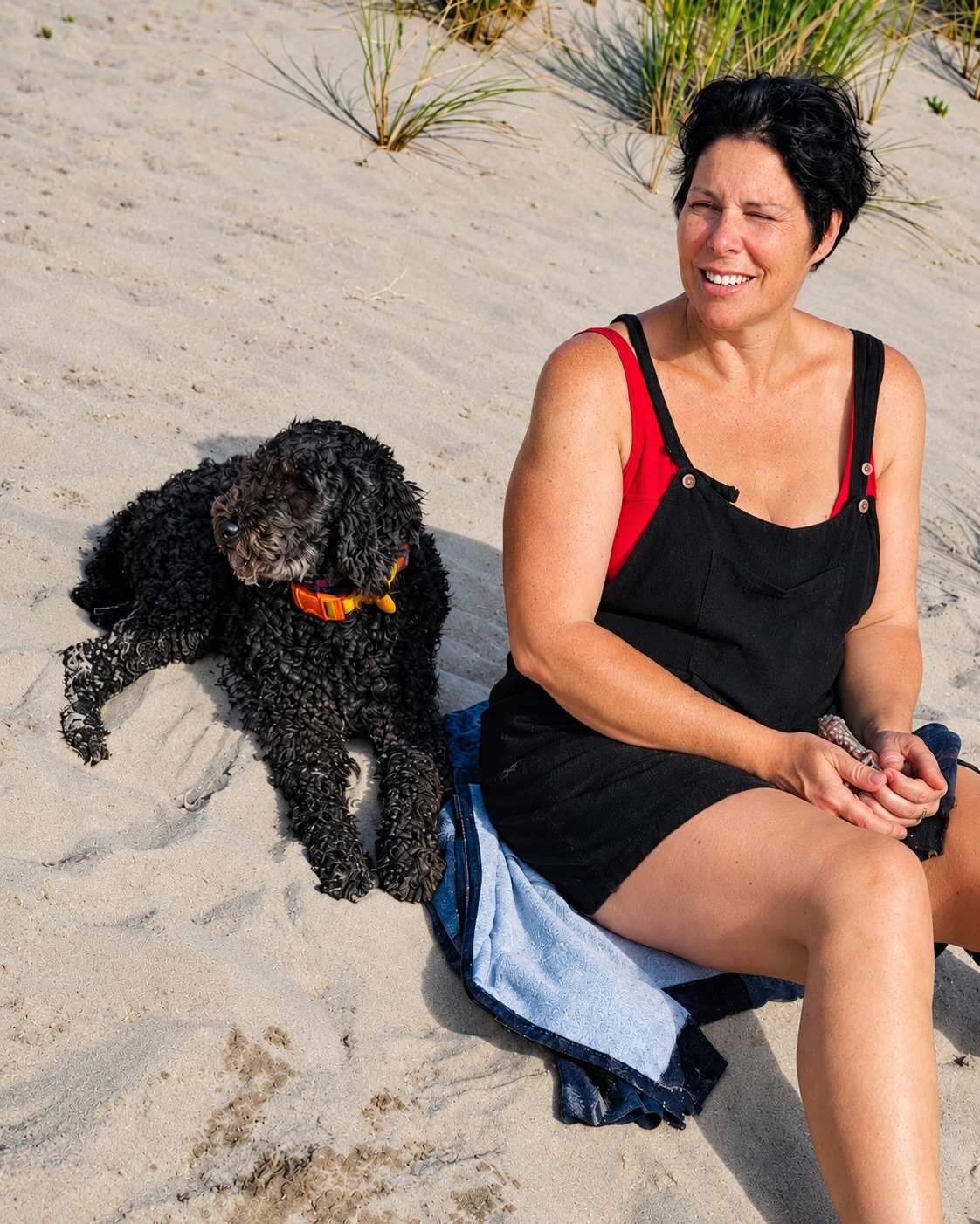 Lyd and Daisy sitting together on the sand beside beach grass